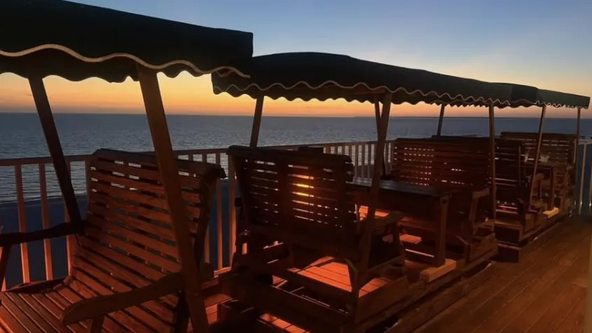 glider chairs lined up during sunset with red lights under them for under glow