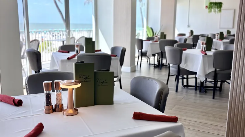fine dining restaurant with white table cloths, grey chairs, red rolled silverware  