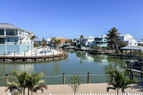 overlooking water, white fence, palm trees, houses, blue skies, a boat dock